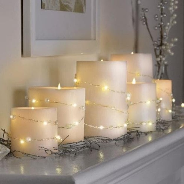 white candle of varying heights on a mantle Winter Decorating