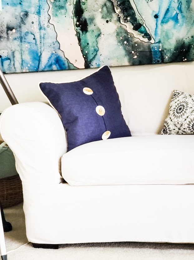 Creamy summertime slipcovered sofa with coastal inspired pillow