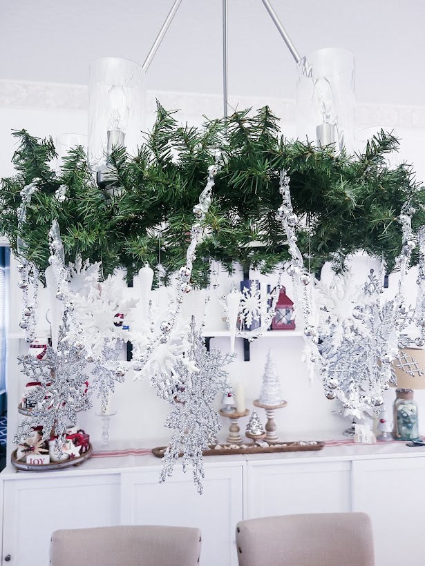 A picture of the chandelier with silver ribbon draped along the greenery.