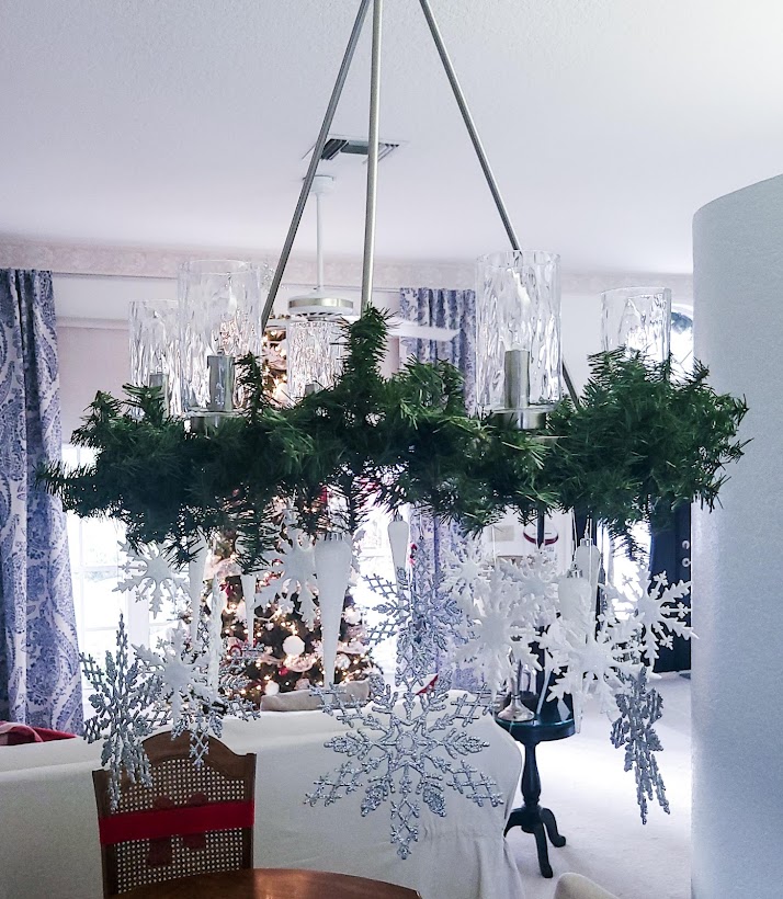 A picture of the chandelier with faux pine garland around the top rim