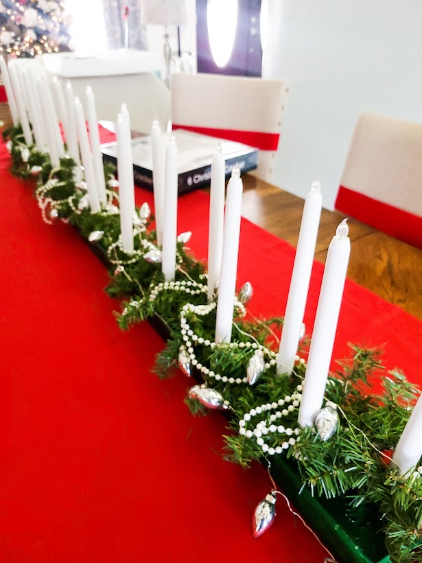 A picture of my candle holder decorated with lights, pearls and pine boughs.