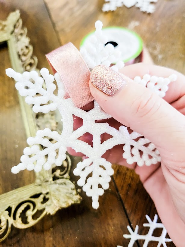 Threading the ribbon through the holes in the snowflake.