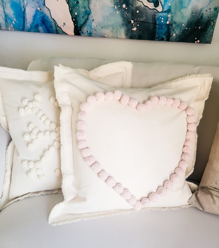 A picture of both pompom pillows (snowflake and heart) on my white slip-covered sofa.