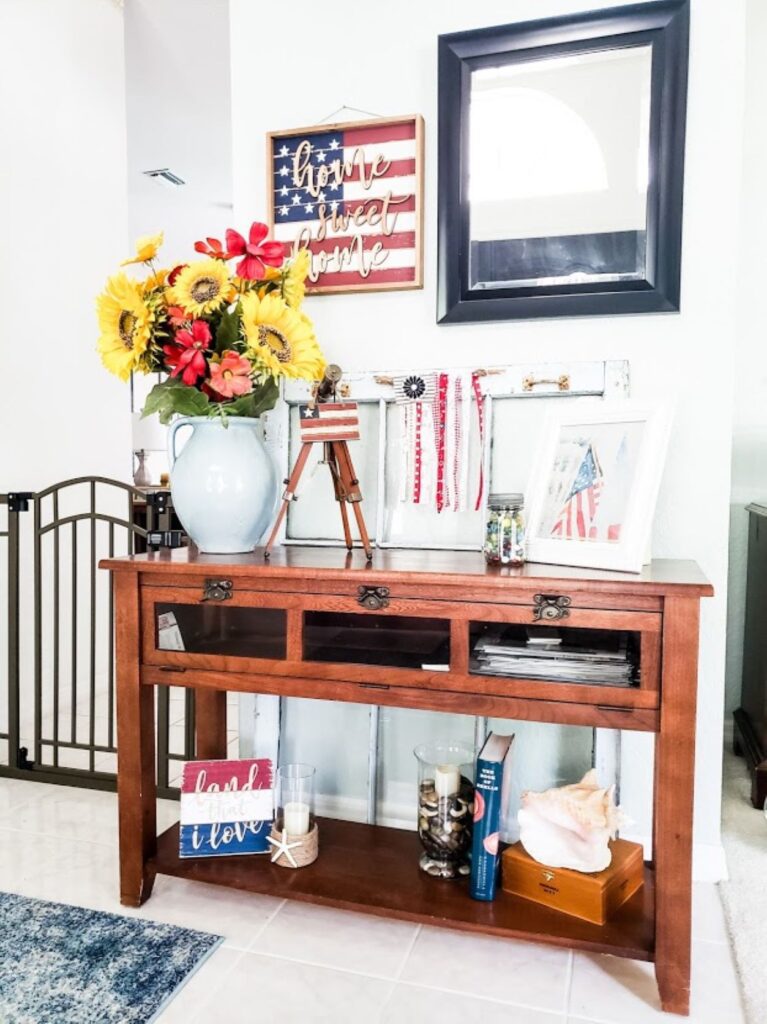 A picture of my summer entryway with a vase of sunflowers and patriotic decor all ready for the 4th of July