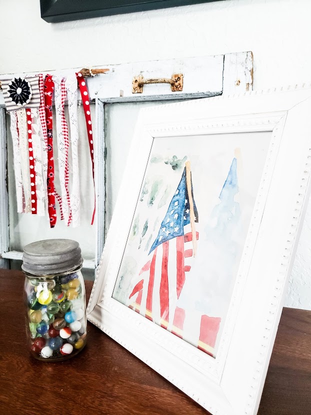A picture of my entryway decorated for summer. A framed printable of the American flag sits on the tabletop.