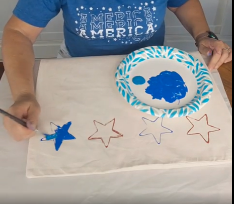 painting blue and red stars on a white pillow cover