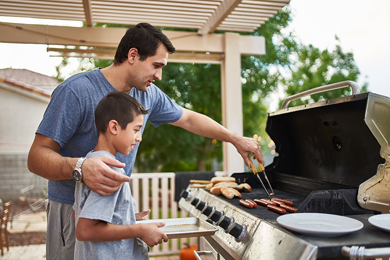 man and boy cooking outdoors on a grill