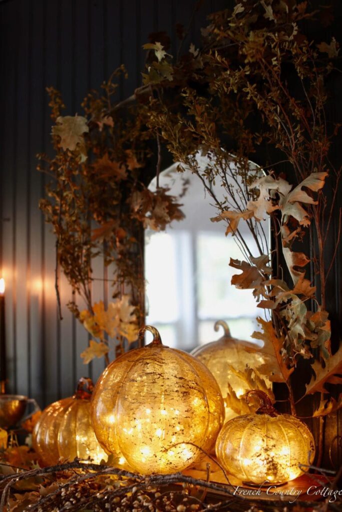 black wall with orange glass pumpkins and fall branches