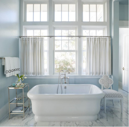 bathtub with large window and blue walls