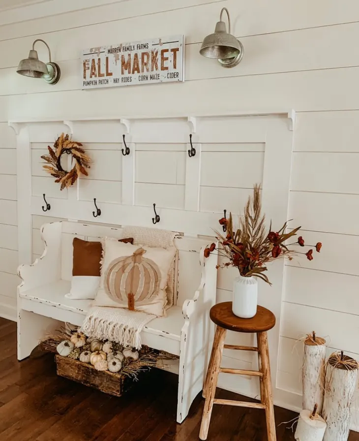 white entryway with accent wall and bench decorated for fall