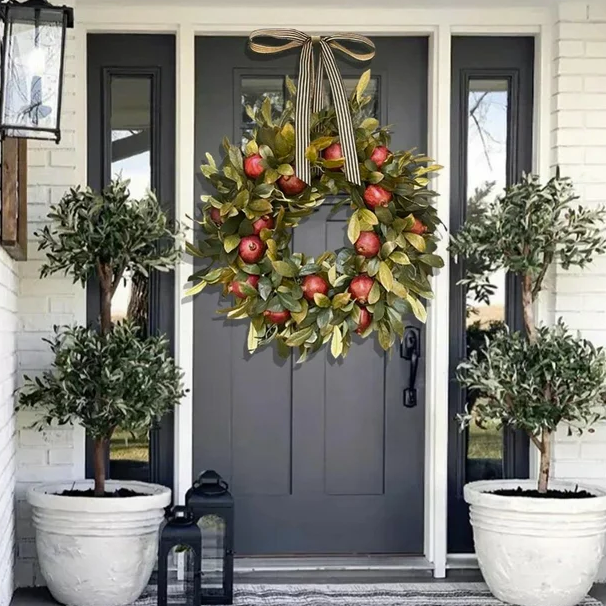 black front door with 2 white potted trees and apple and magnolia leaf wreath