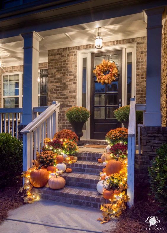 front porch with pumpkins and string lights