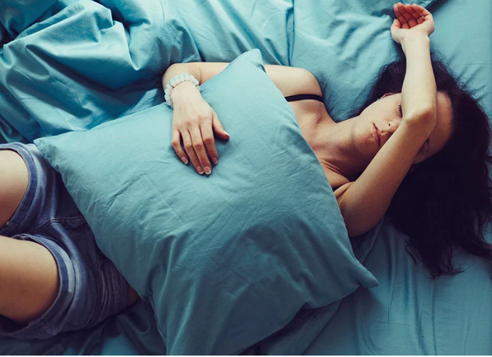 woman sleeping on bed with blue sheets