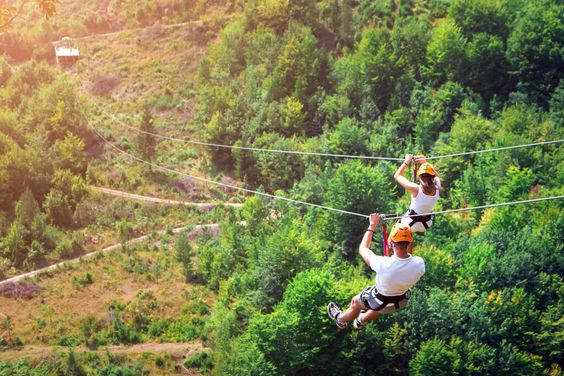 man and woman zip lining in the mountains
