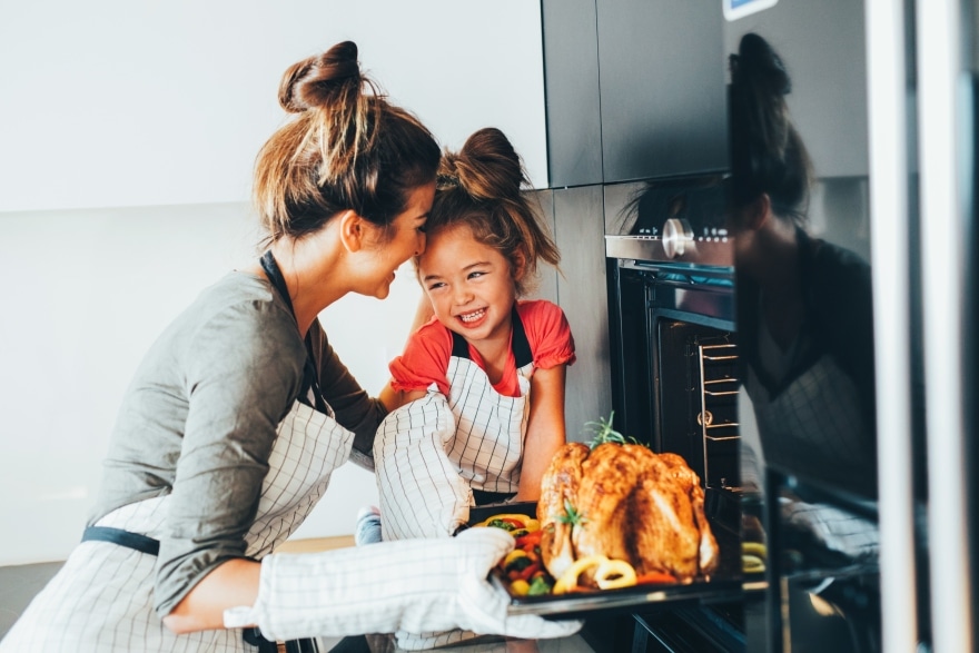 woman and little girl putting a turkey in the oven