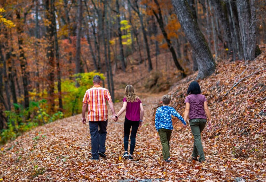 family walking in the woods on autumn leaves