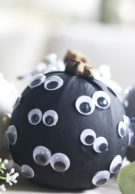 pumpkin painted black with googly eyes glued all over