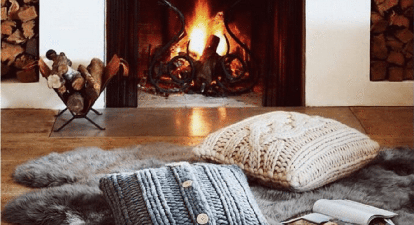 pillows in front of a roaring fire in the fireplace