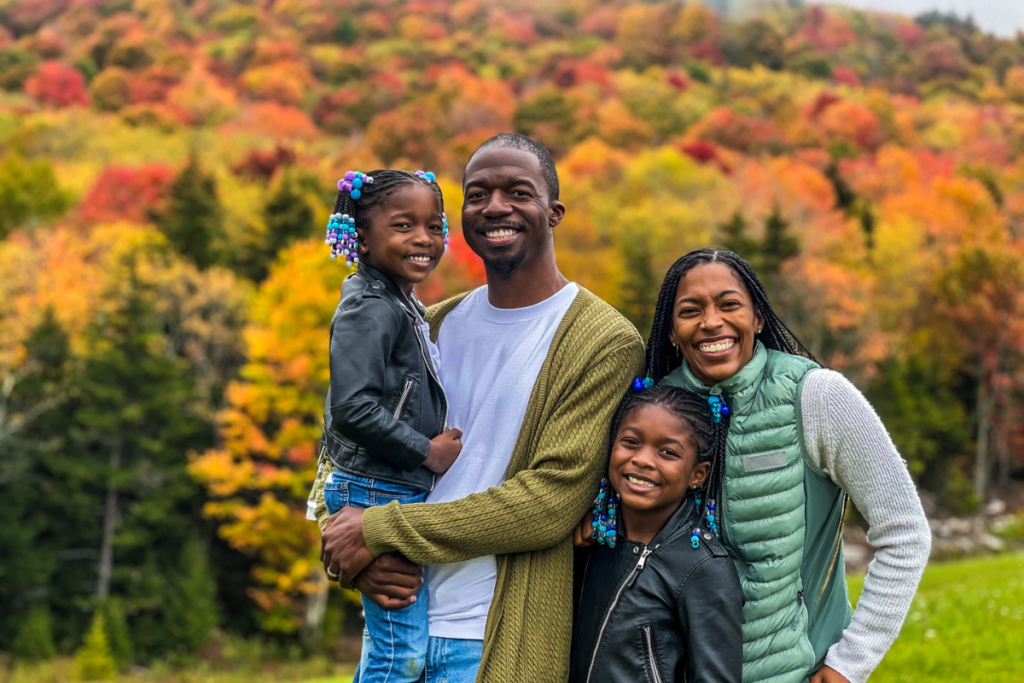 family in front of colorful autumn trees
