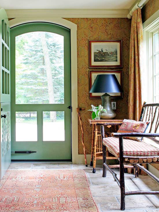 entryway with green screen door, bench and table with lamp