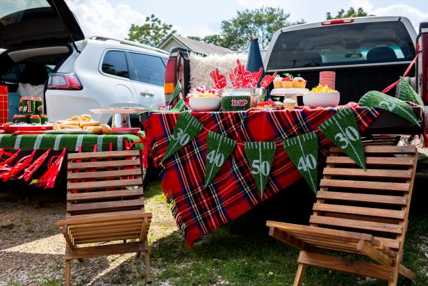 two outdoor chairs with table covered with a red plaid tablecloth and turf yard marker garland