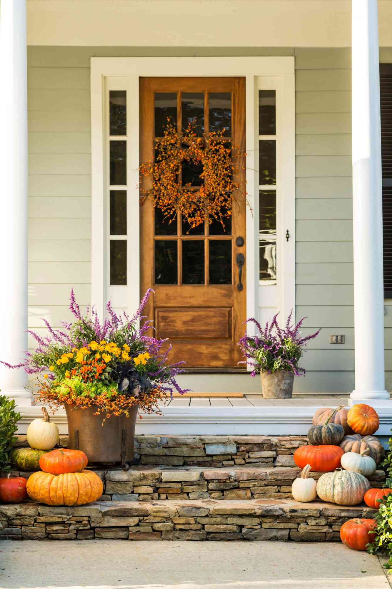 front porch decorated with fall pumpkins and flowers