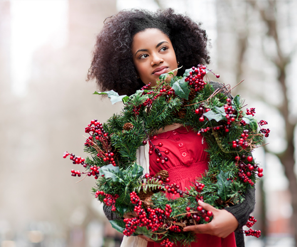 woman holding a Christmas wreath with red berries