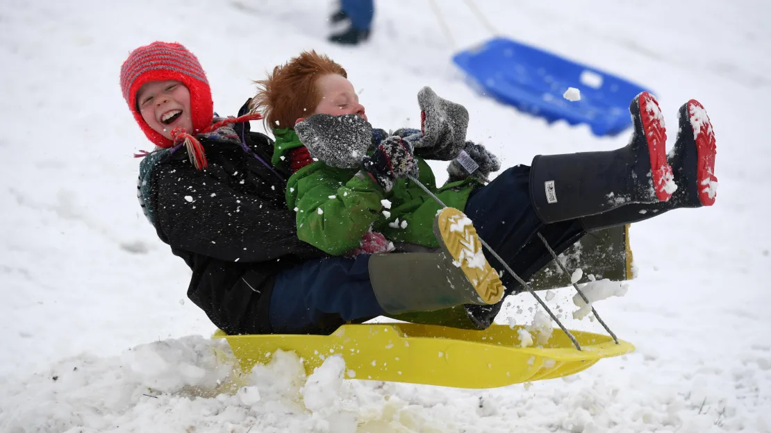two boys on a sled in the snow