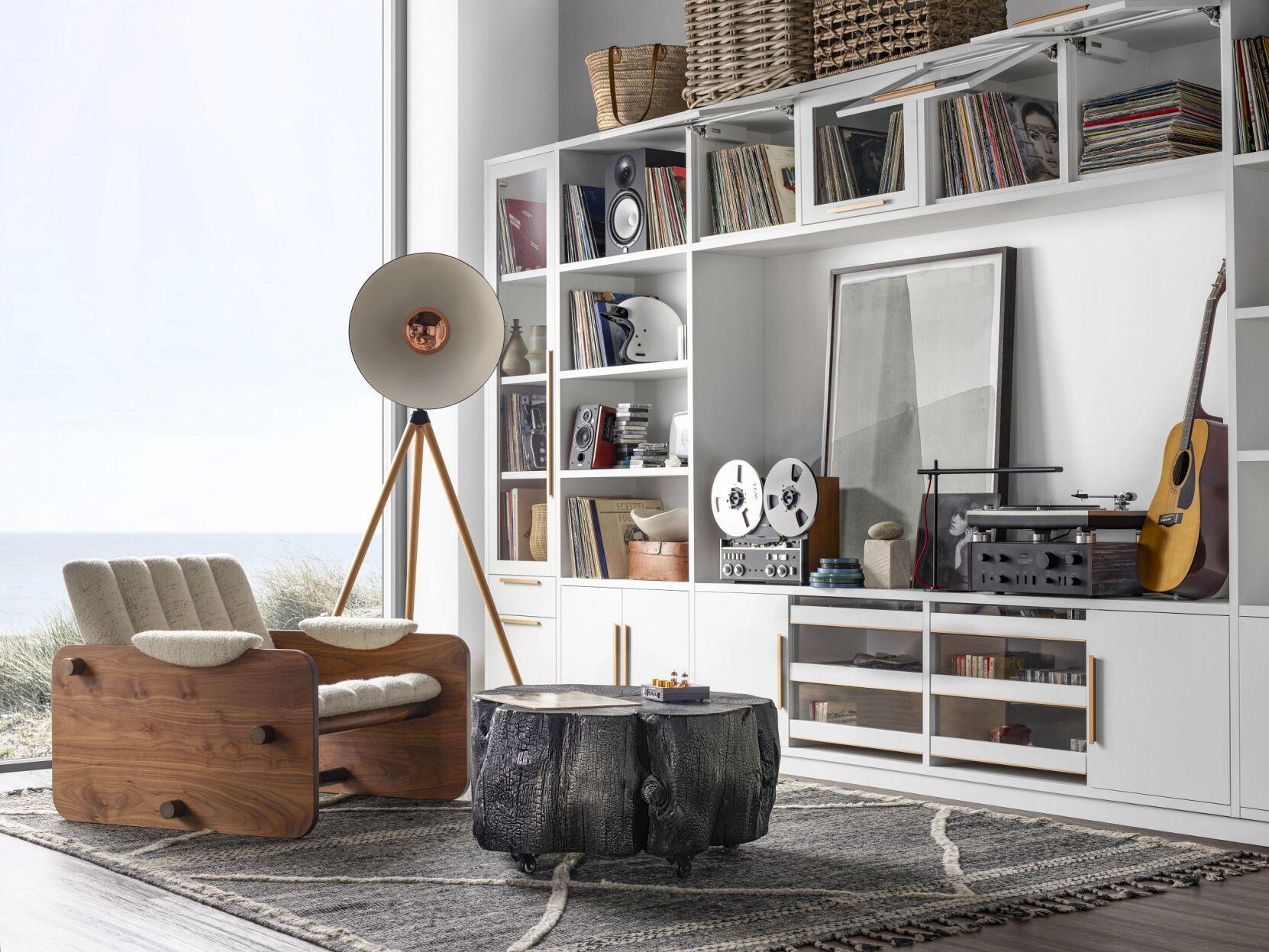 white living room with a brown chair, bookshelves and a large window home is more than a location