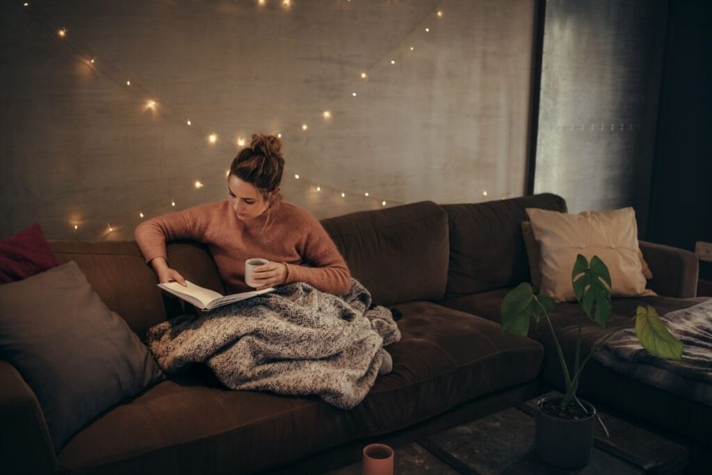 woman reading on a sofa with a blanket the-soul-of-the-home