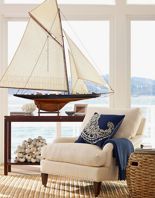 white upholstered chair and a model of a ship by a large window overlooking a lake