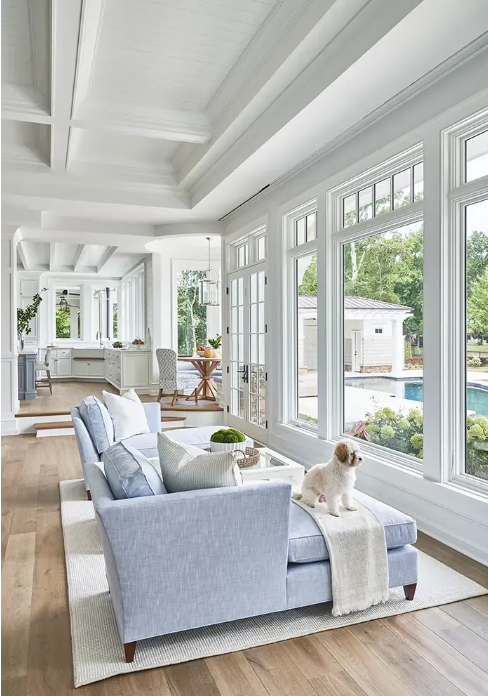 white living room with large windows and blue upholstered furniture