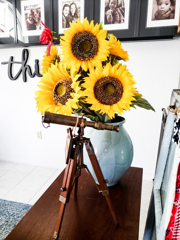 sunflowers in a blue vase and a miniature nautical spyglass on a table