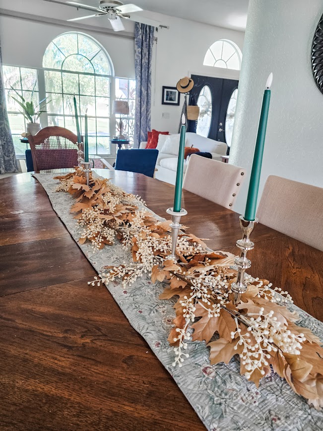 a table with fall florals and silver candlesticks with green candles