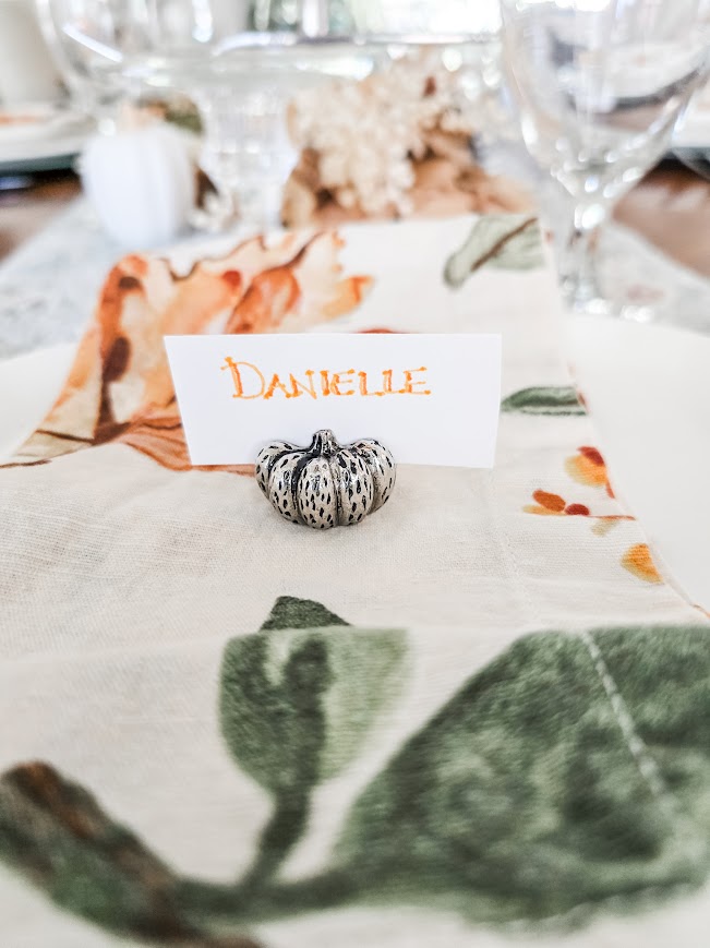 a tiny silver pumpkin place card holder on a fall floral napkin crafting the perfect tablescape