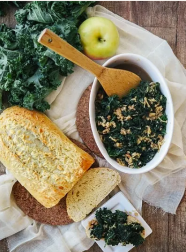 a white oval dish of kale with apples and walnuts and a half loaf of crust bread greta fall side dishes