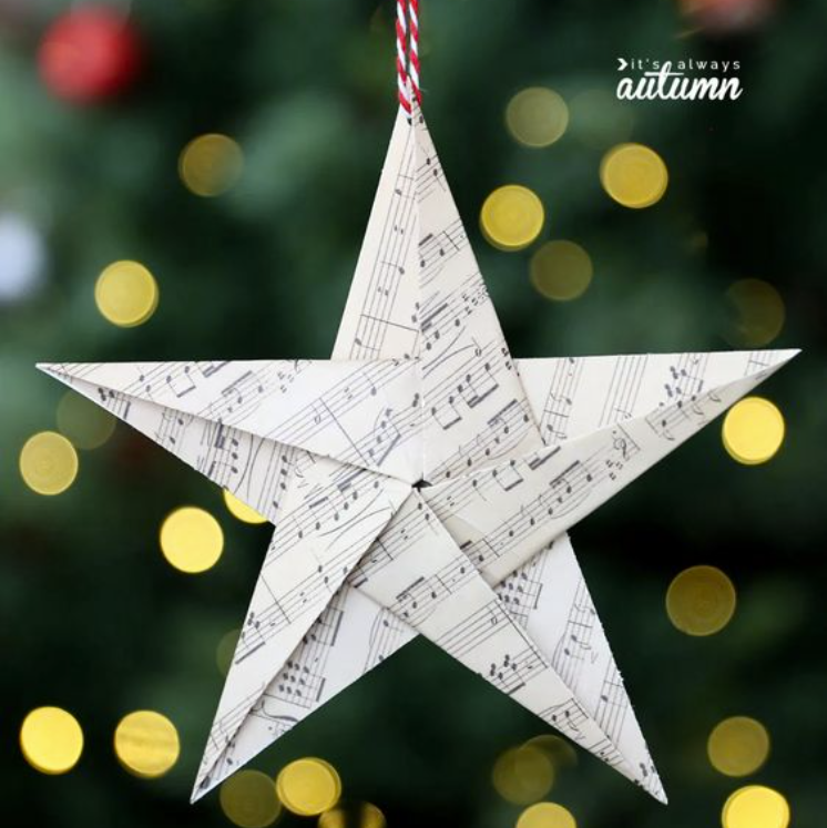 origami star made from book pages with Christmas tree lights shining behind it holiday trends