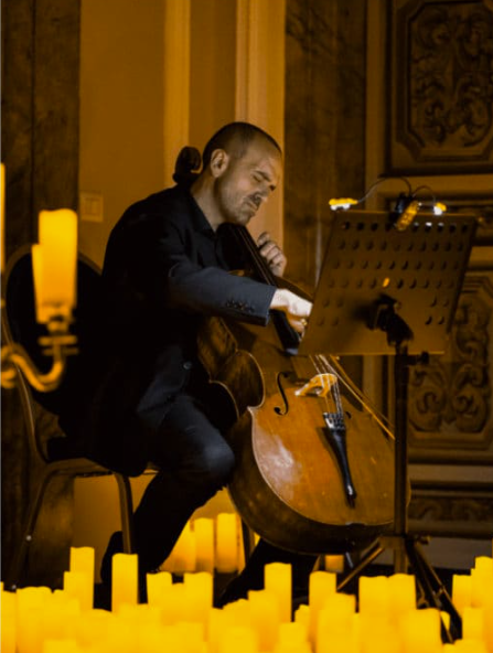 a man playing the cello in candlelight