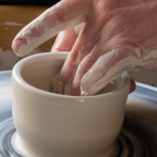 a potter making a cup on a wheel