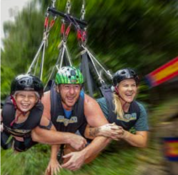 three people zip lining in the jungle