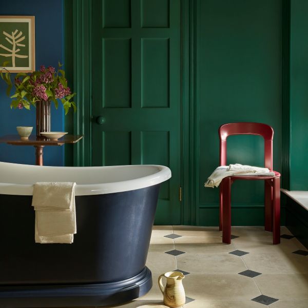 Dark green bathroom walls and doors with a navy blue tub and white tiled floor