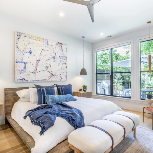 white bedroom with blue and white bedding and a large art piece on the wall