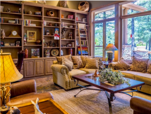 a sofa in front of a floor to ceiling bookcase filled with personal items