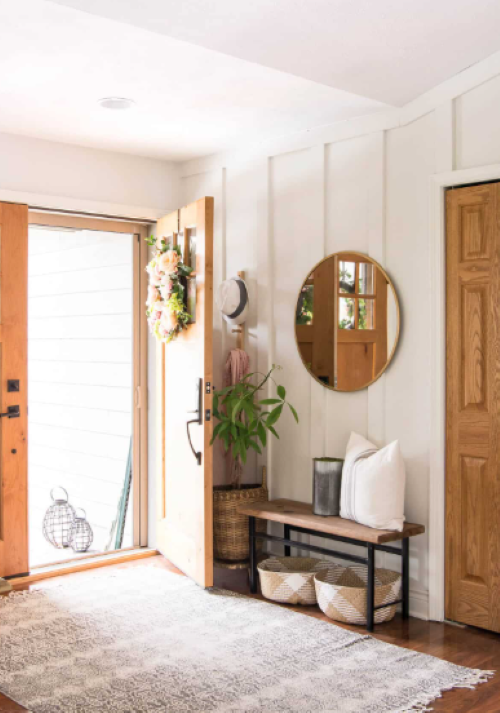 an entryway with a round wall mirror, bench, and wall hook summer decorating for small spaces