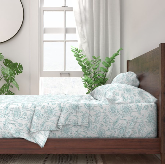 teal and white daisy pattern sheets on a brown wood bed get your home ready for summer