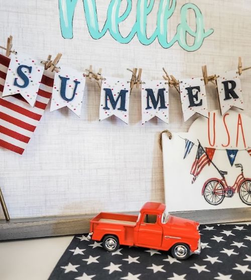 a red toy truck on a flag with the word summer hanging by mini clothespins on a piece of twine get your home ready for summer