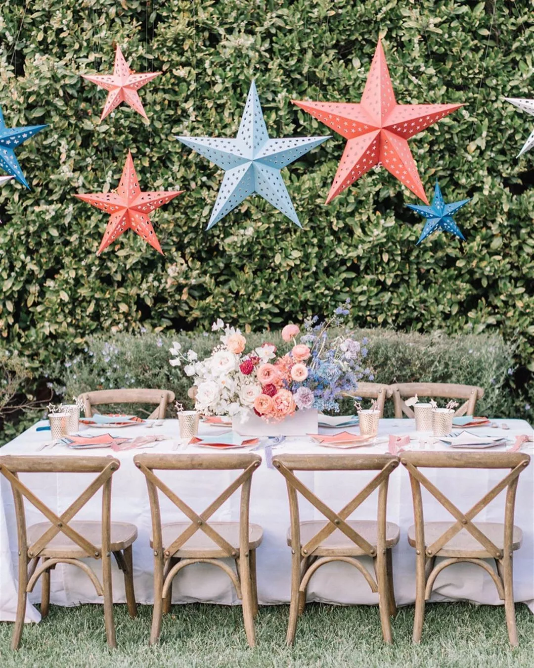 A dining table set outside with red and blue stars hanging overhead