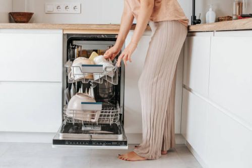 a woman loading a dishwasher how to have a clean home all summer