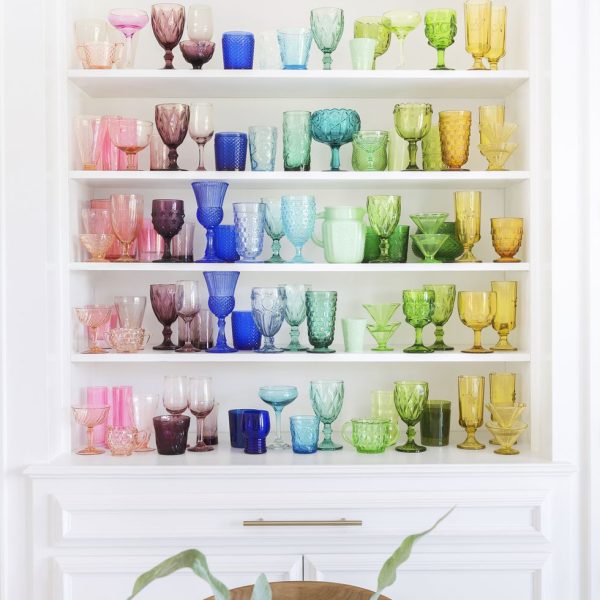 Depression glass arranged by color on a shelf