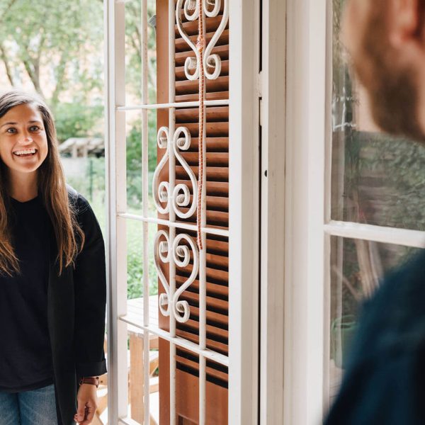 two people at a door greeted by another person